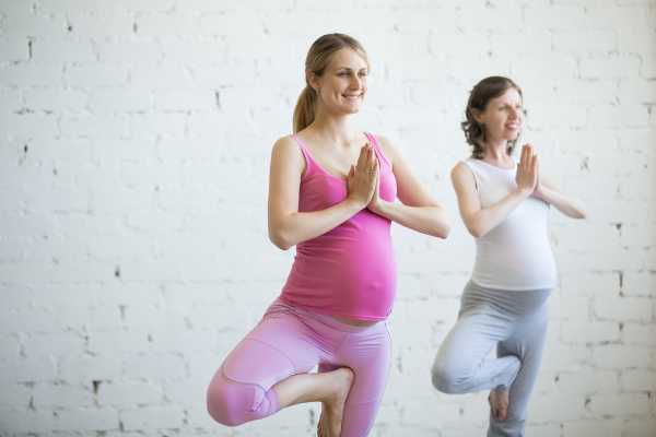 Pregnant young woman doing prenatal yoga. Tree pose 